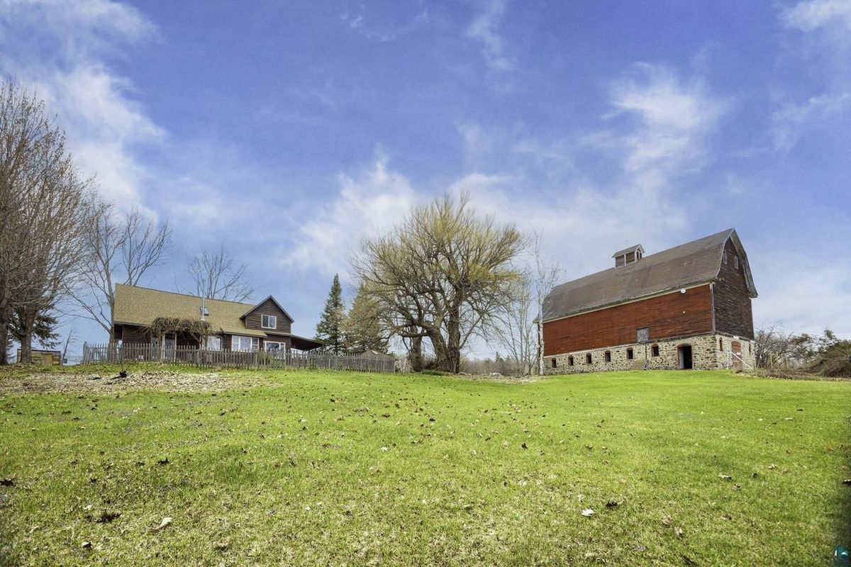 The farmhouse and the barn seen across the open field under a wide sky.