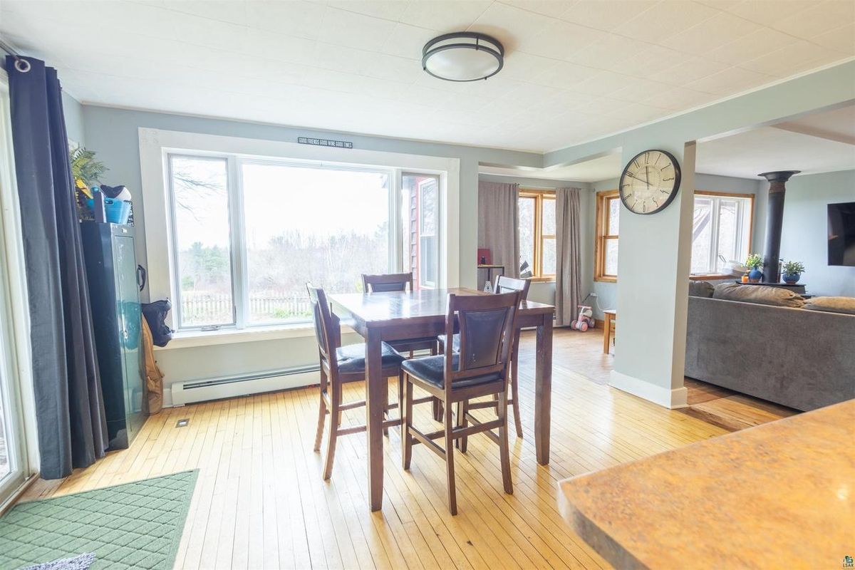 Dining area with a wood table beside a wall of windows that open to the yard.