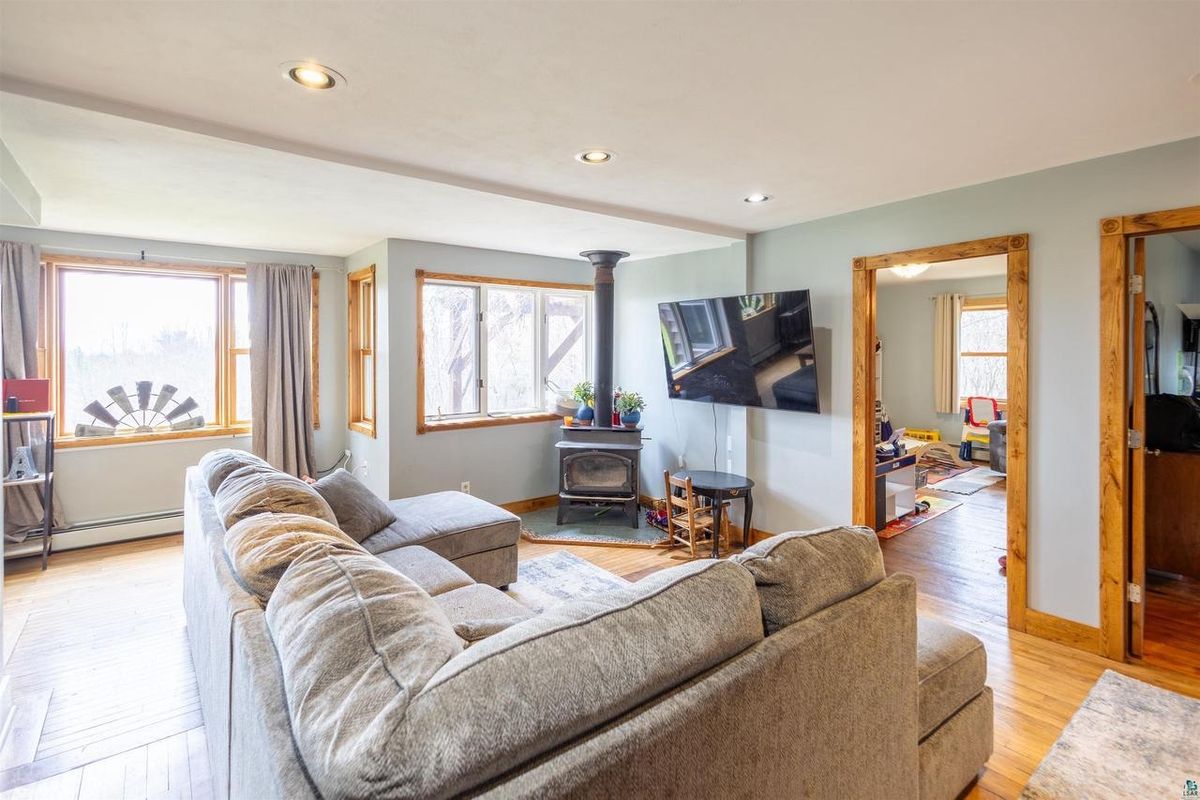 Living room sectional facing the wood stove, with the dining area beyond.