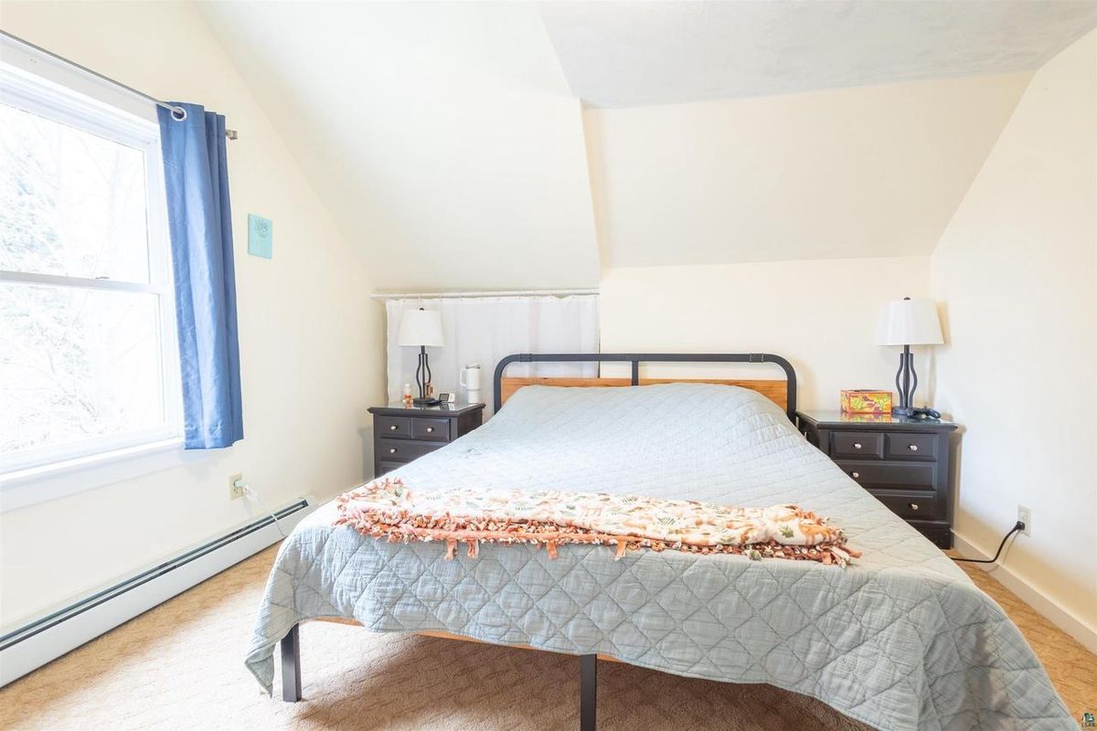 Upstairs bedroom tucked under the roofline, with a window at the gable end.