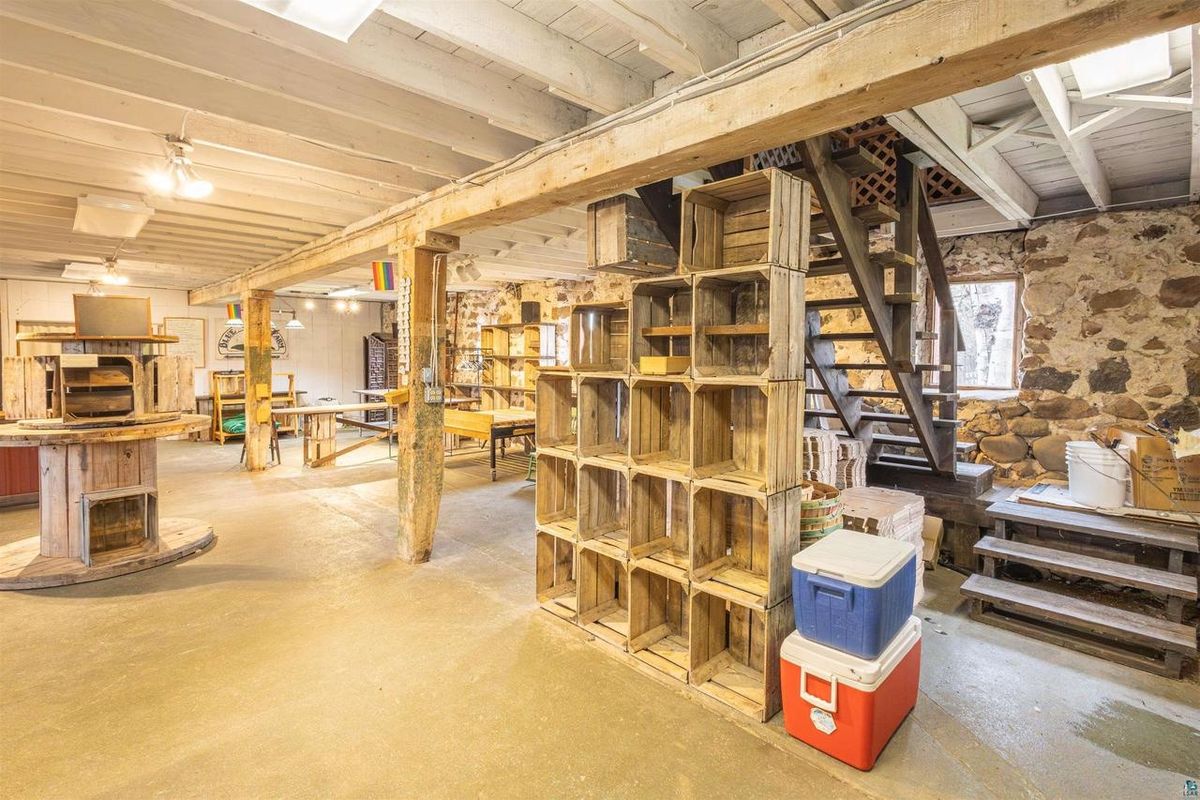 Inside the barn's lower level: whitewashed beams, timber posts, and fieldstone walls.