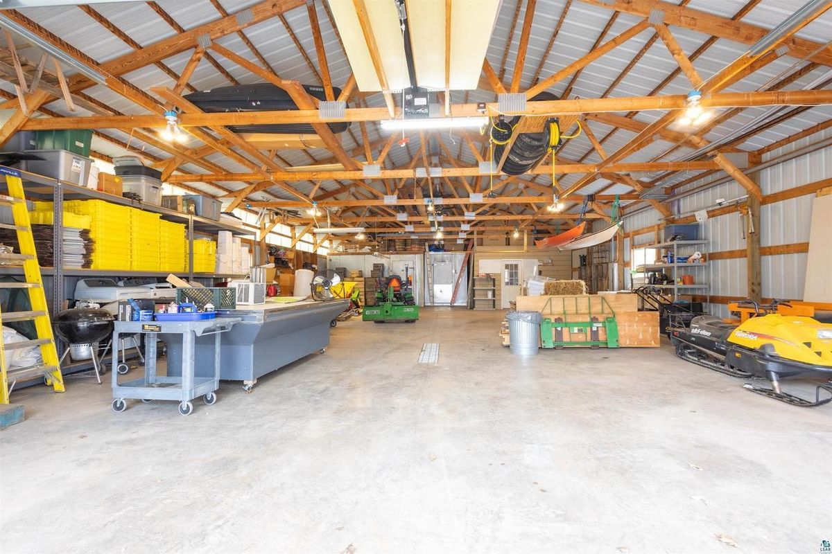Inside the pole barn: an open bay under wood trusses, with shelving along the walls.