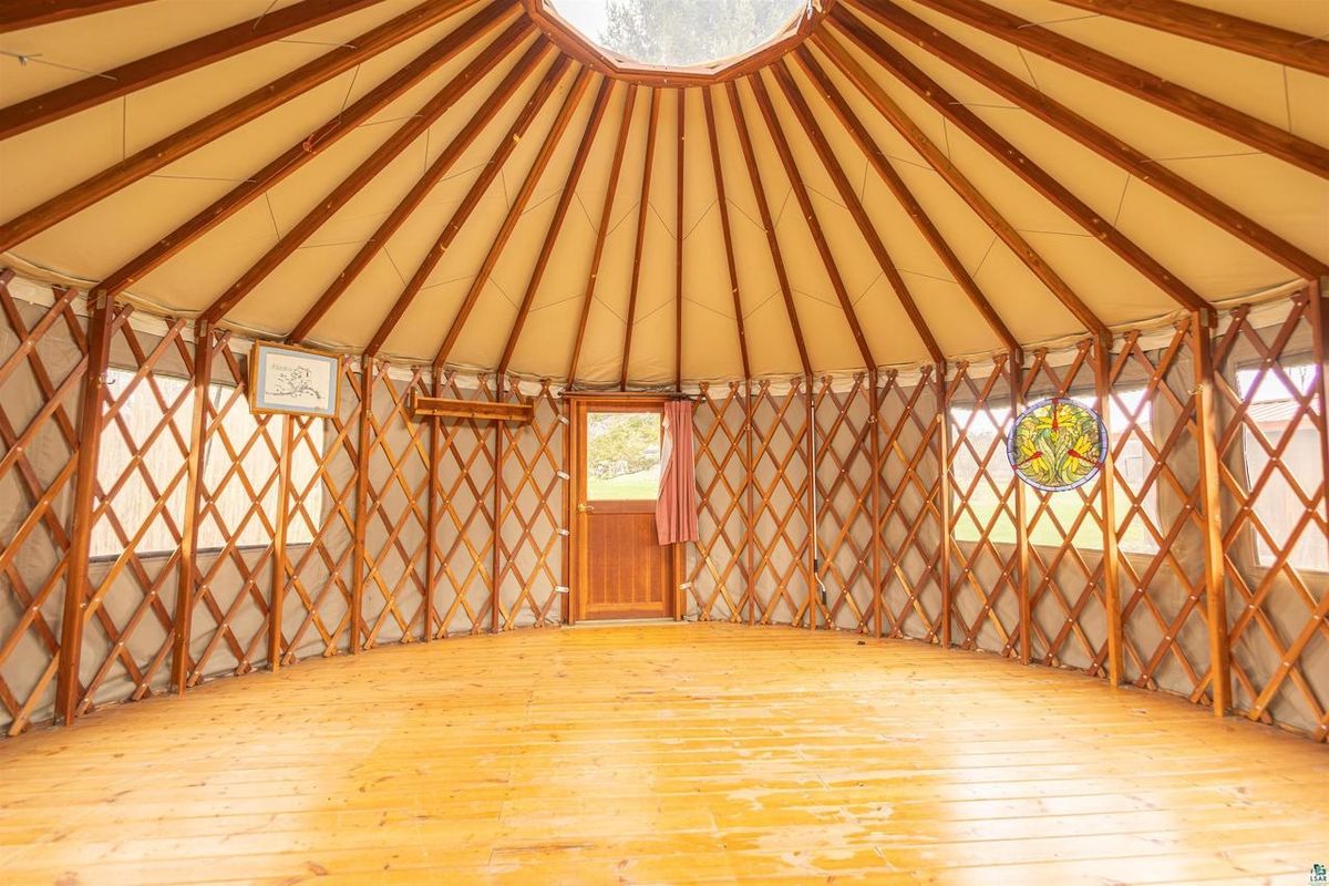 Inside the yurt: lattice walls, radiating roof poles, and a wood floor.