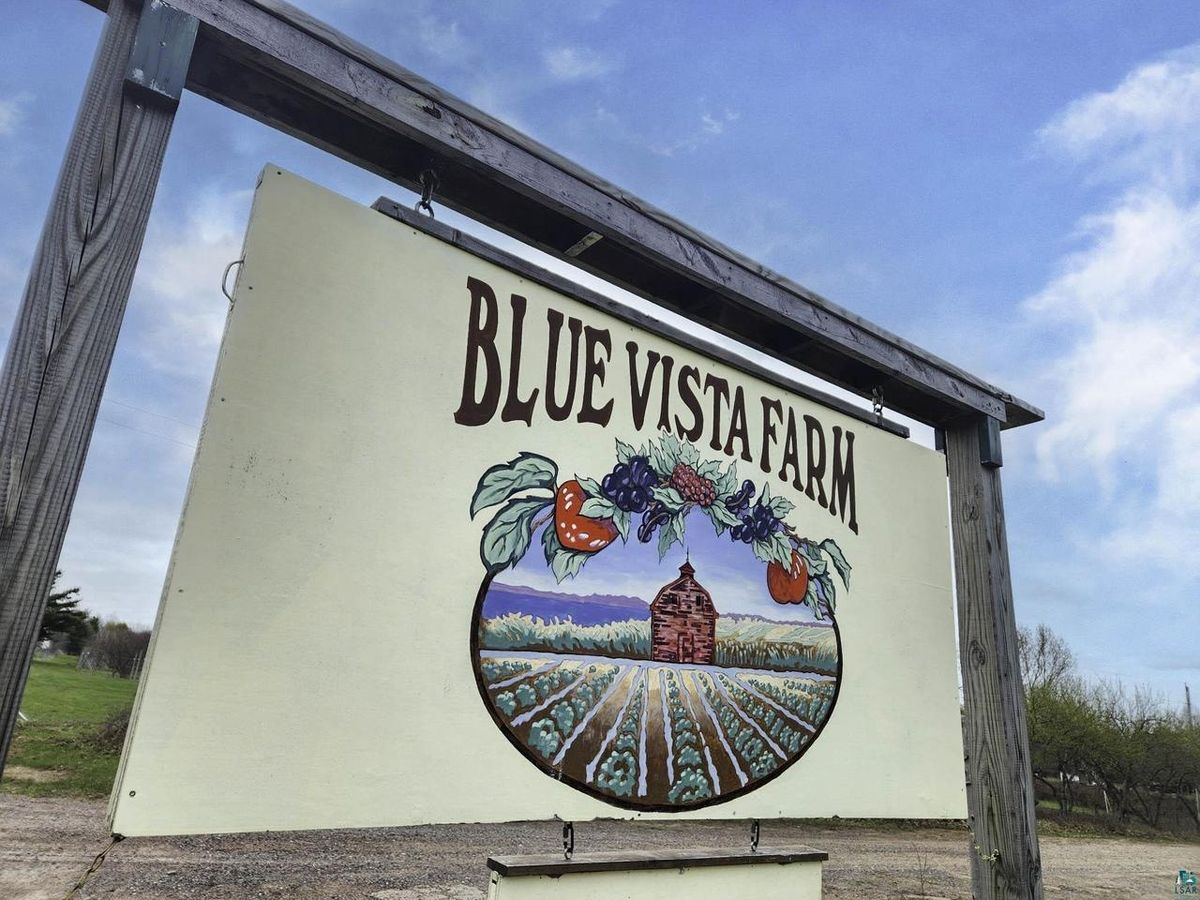 The painted Blue Vista Farm sign at the road.