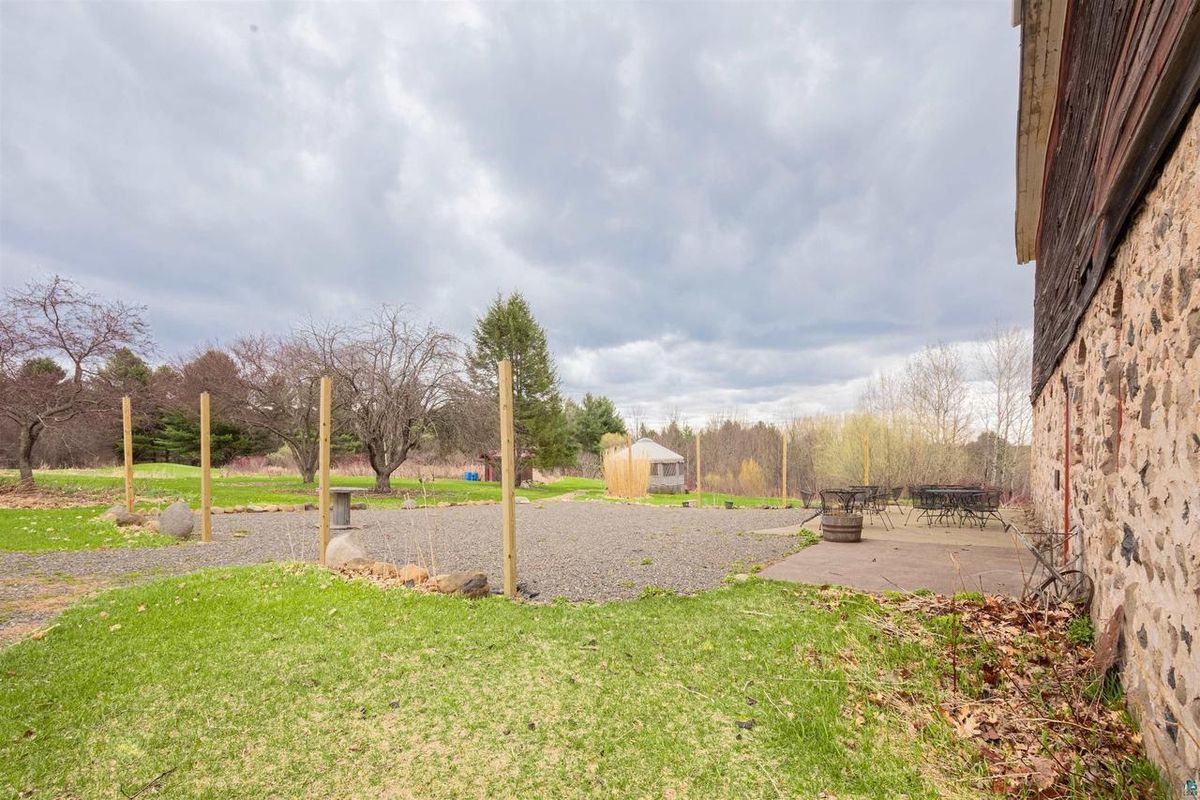 Gravel patio beside the barn's stone wall, with tall posts strung for lights.